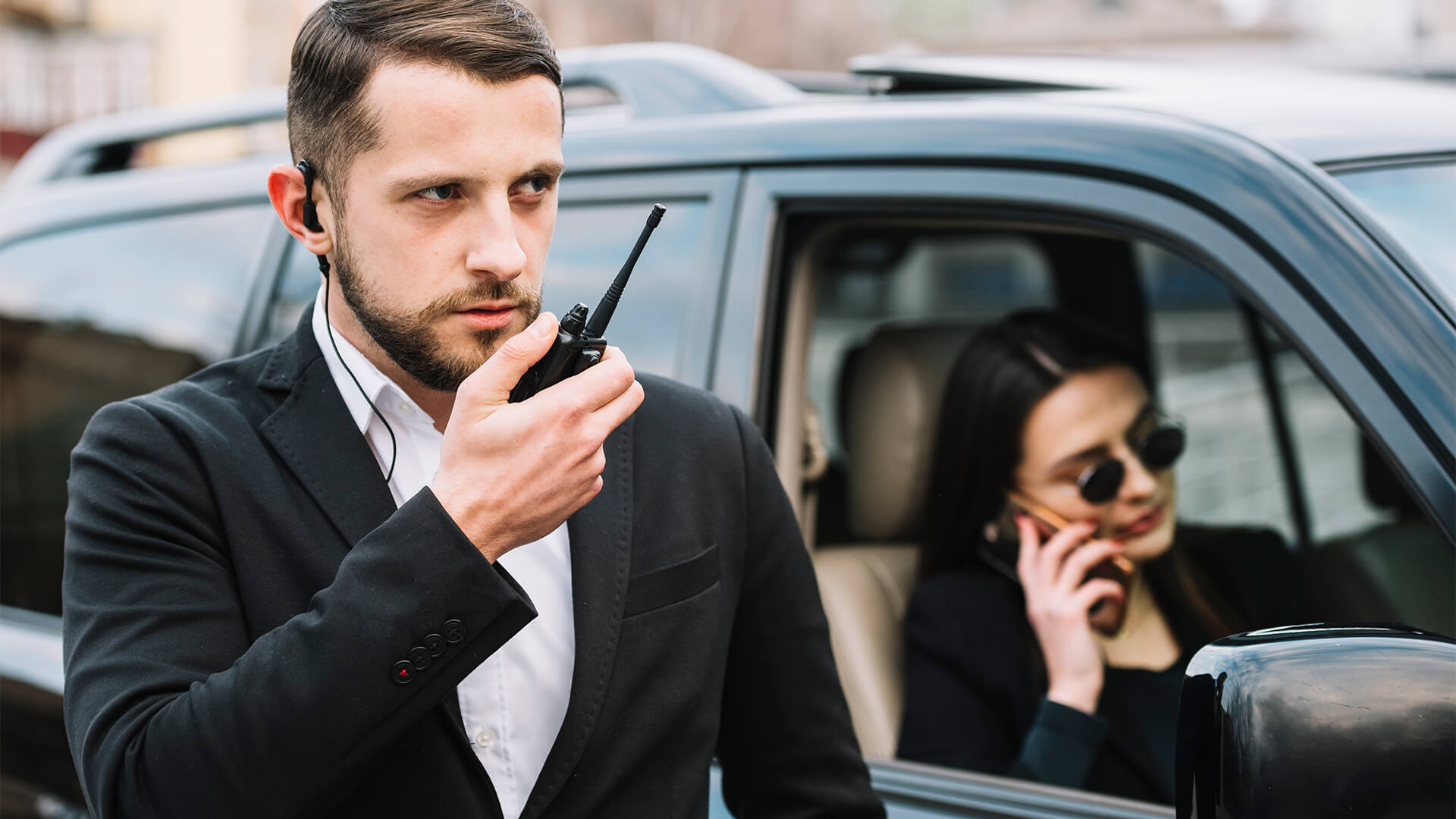 Personenschützer mit Funkgerät an einem Fahrzeug